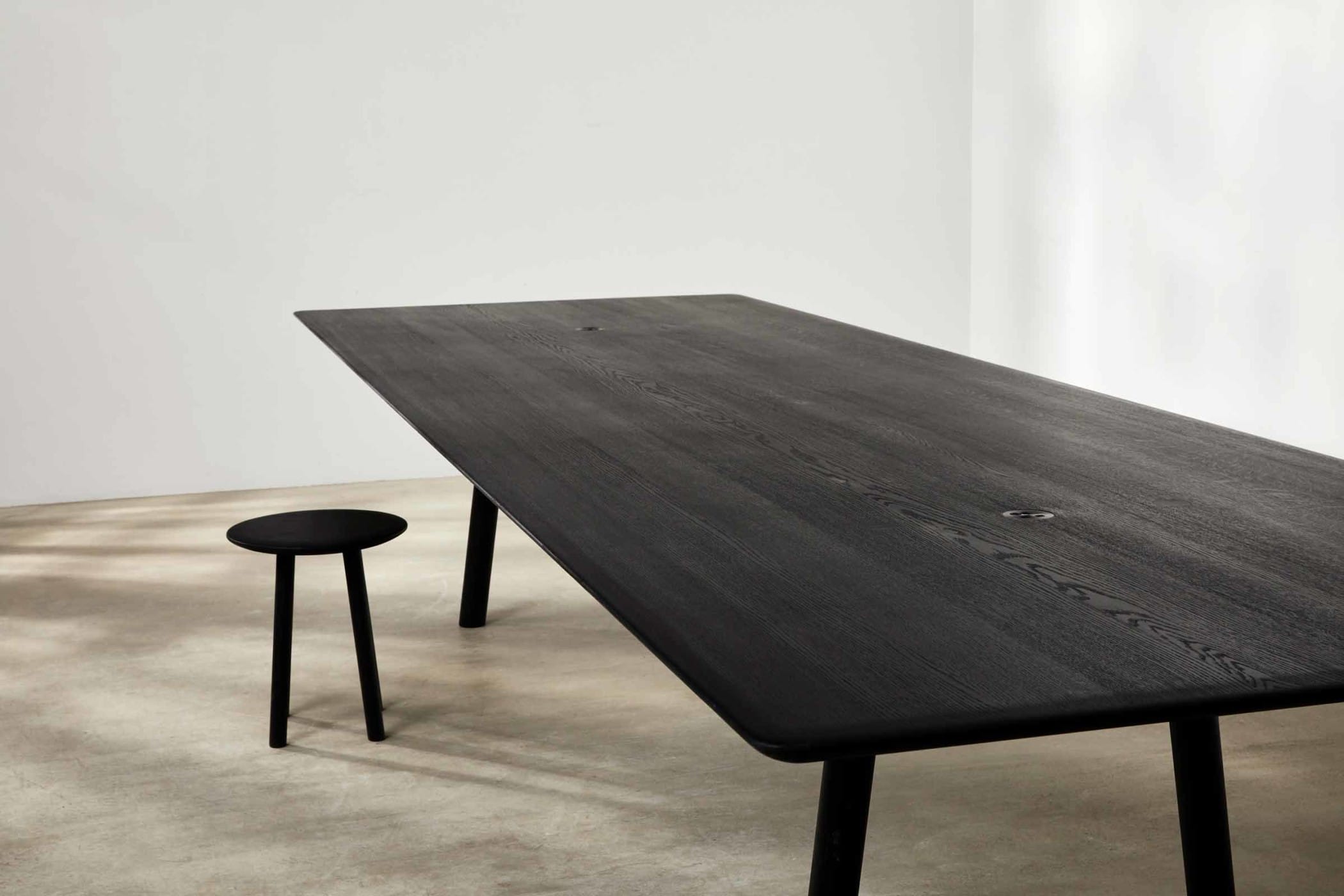 large ebonised oak meeting table with a small ebonised oak stool